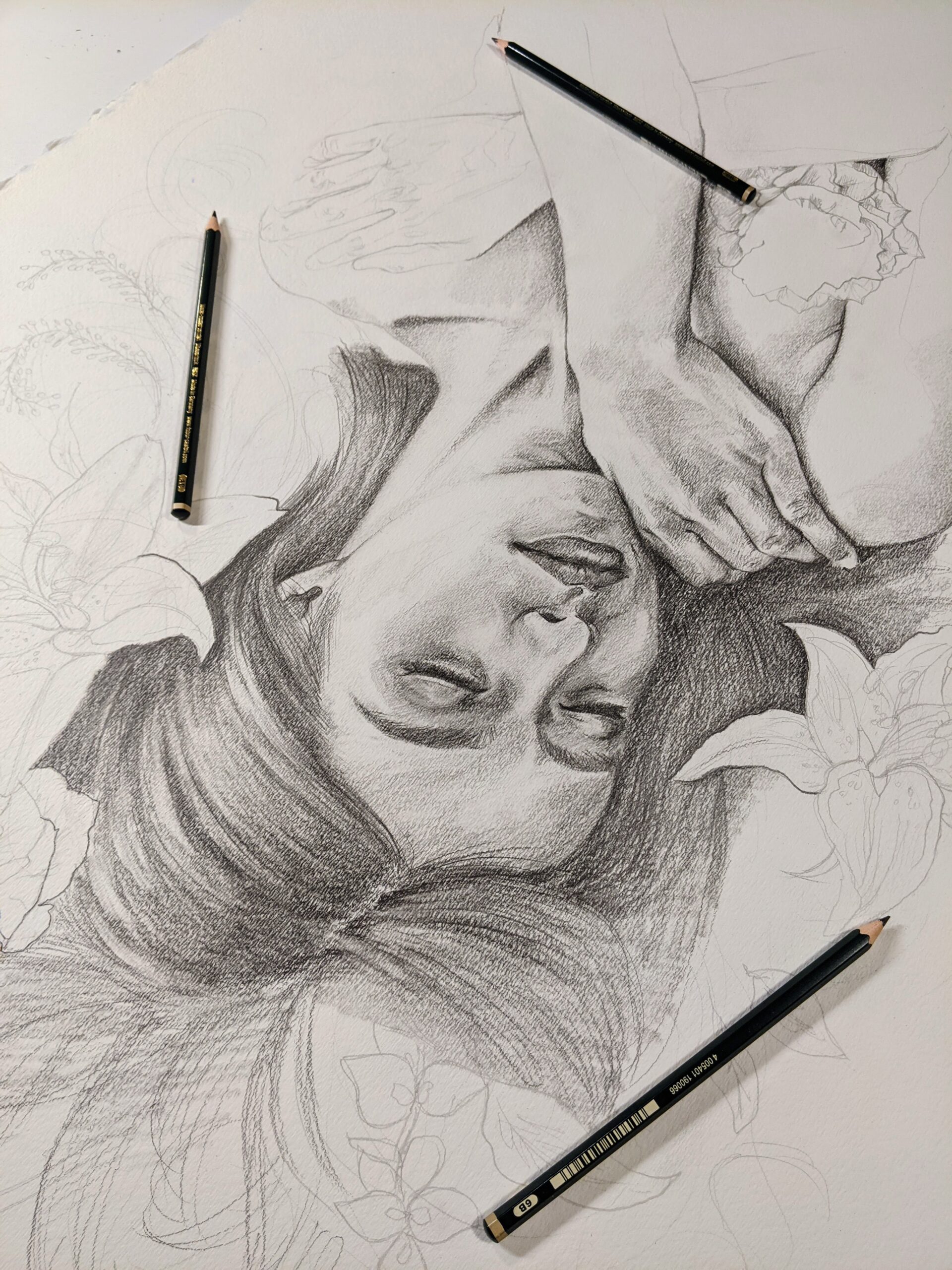 Pencil drawing of a sleeping woman with one hand on her shoulder. There are three pencil laying on the paper.